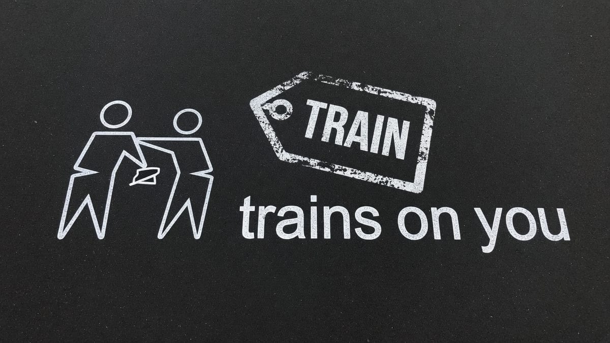 Light chalk on dark asphalt, a price tag stamped TRAIN, and the words trains on you